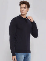 A man wears a 98degreenorth dark navy Merino wool polo sweater, styled with blue jeans against a light gray background.