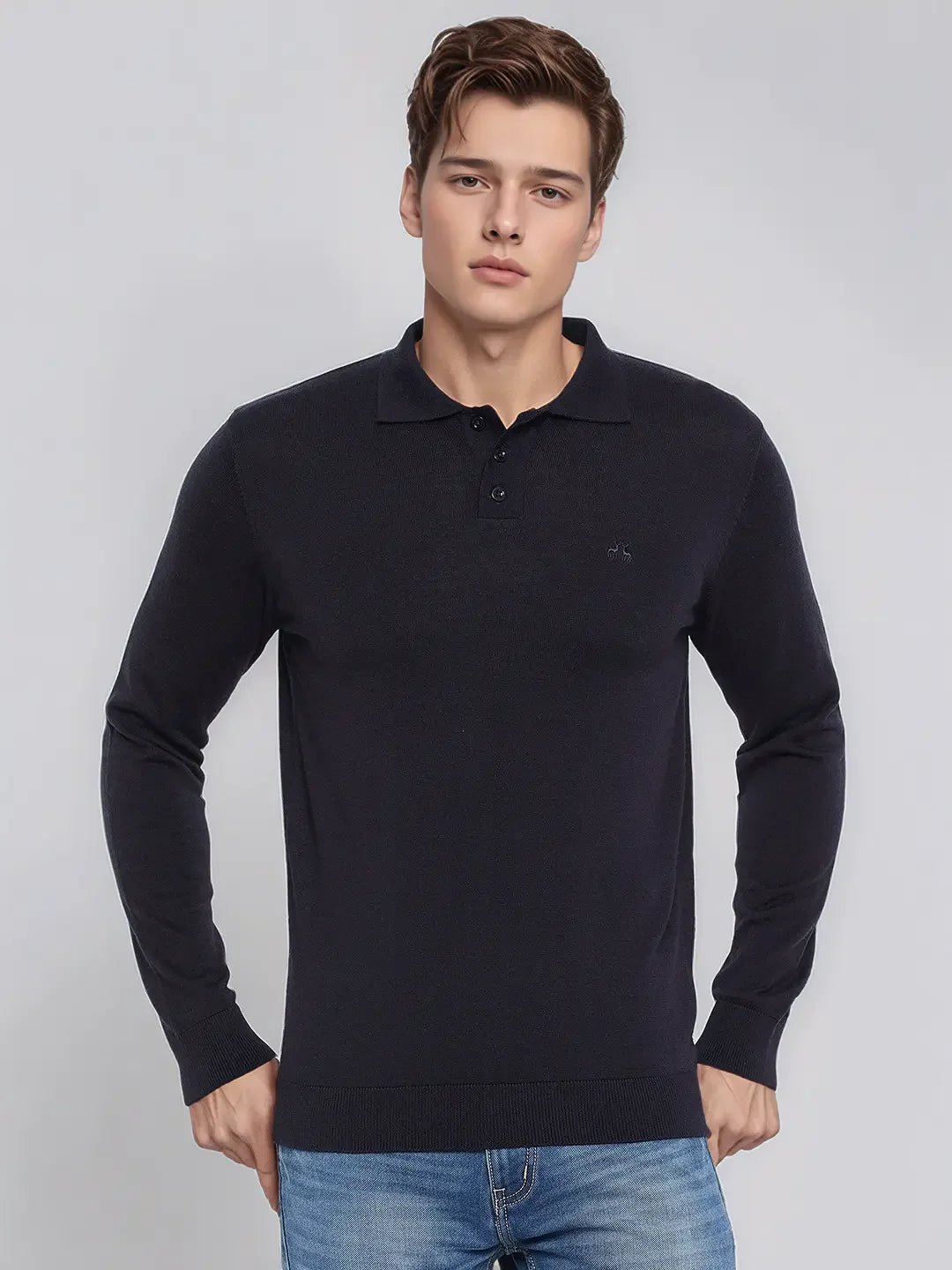 A man wears the 98degreenorth Men’s Dark Navy Merino Wool Polo Sweater with blue jeans against a plain light gray background.