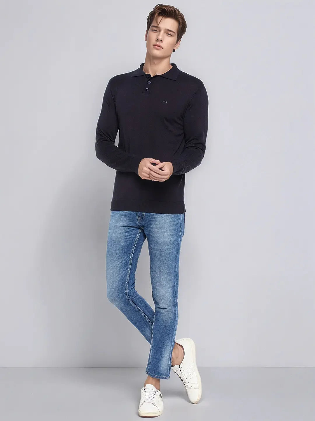 A man in a 98degreenorth dark navy Merino Wool Polo Sweater stands against a plain gray background.