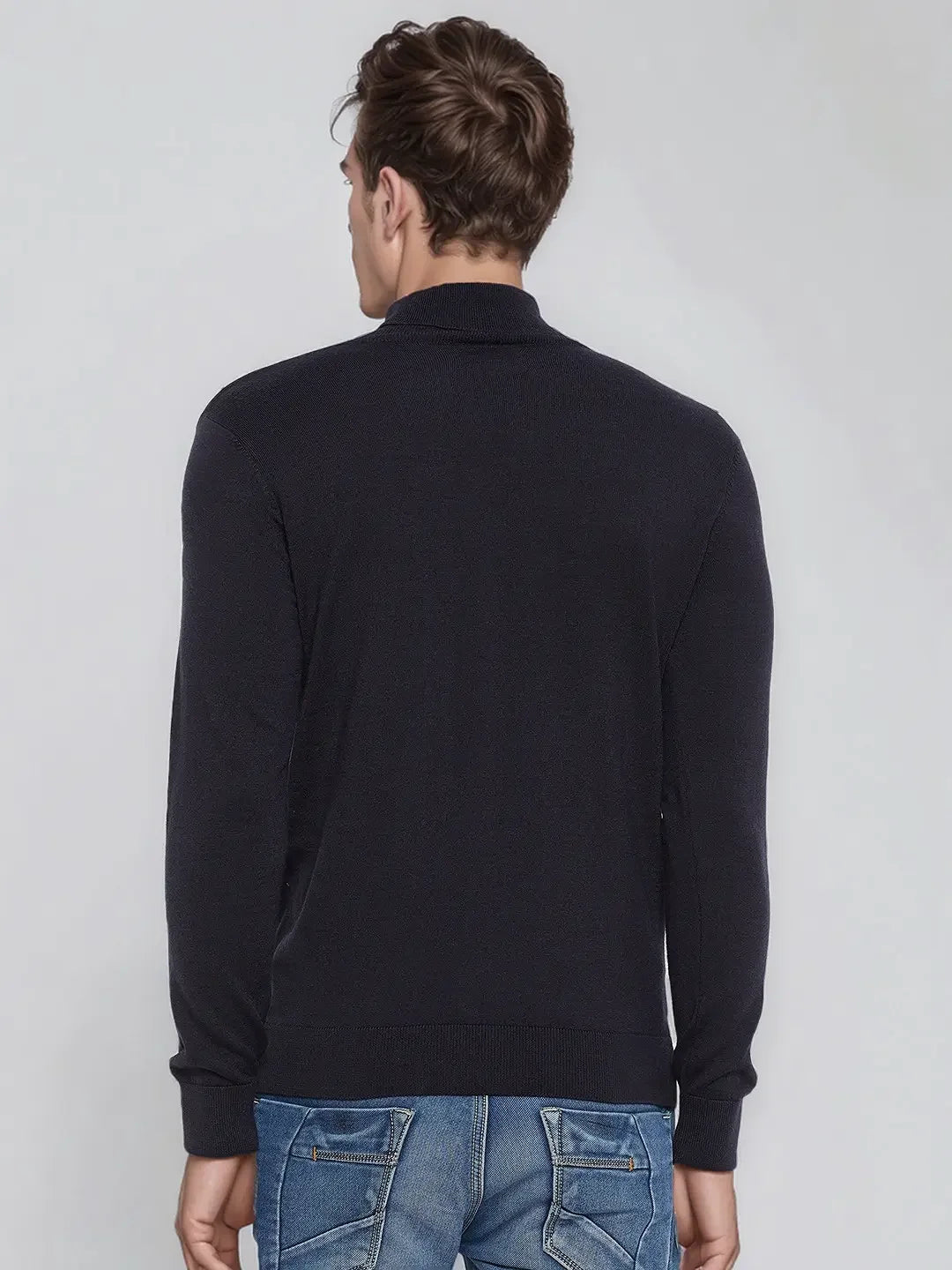 A man in a 98degreenorth Men’s Dark Navy Merino Wool Turtle Neck Sweater stands with his back to the camera.