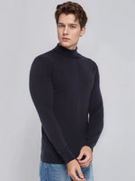 Young man in 98degreenorth Men's Dark Navy Merino Wool Turtle Neck Sweater and blue jeans on a light gray background.