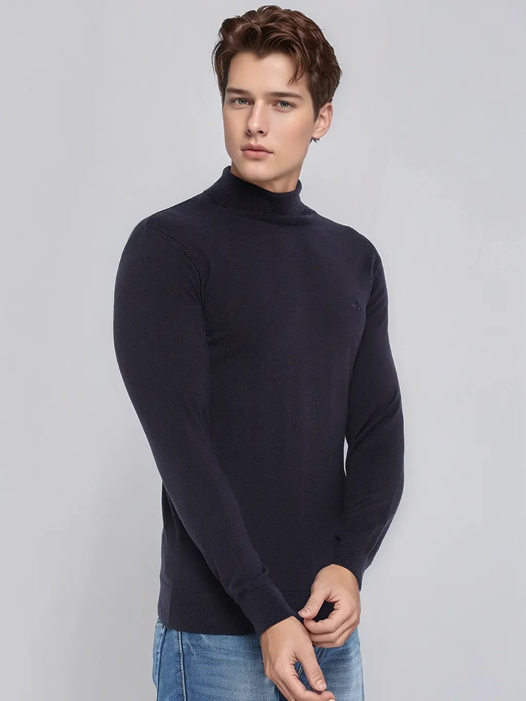 Young man in 98degreenorth Men's Dark Navy Merino Wool Turtle Neck Sweater and blue jeans on a light gray background.