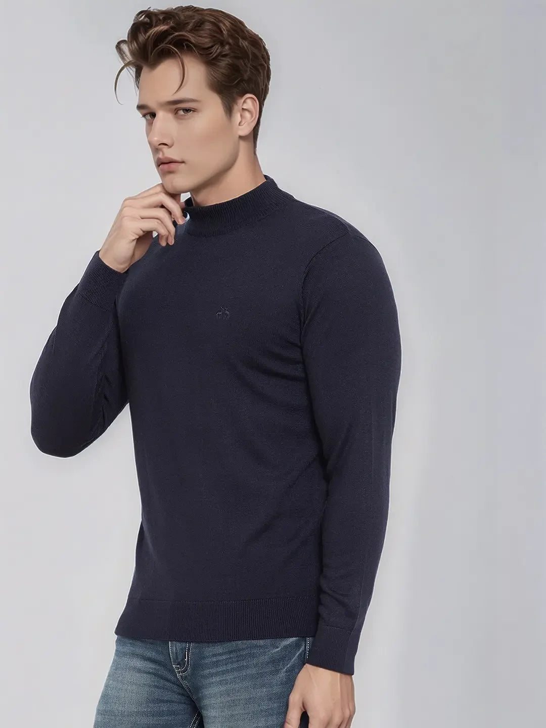 A man wears the 98degreenorth Men’s Dark Navy Merino Wool Turtle Neck Sweater against a light gray background in India.