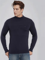 A man in a 98degreenorth Men’s Dark Navy Merino Wool Turtle Neck Sweater and blue jeans looks left against a plain background.