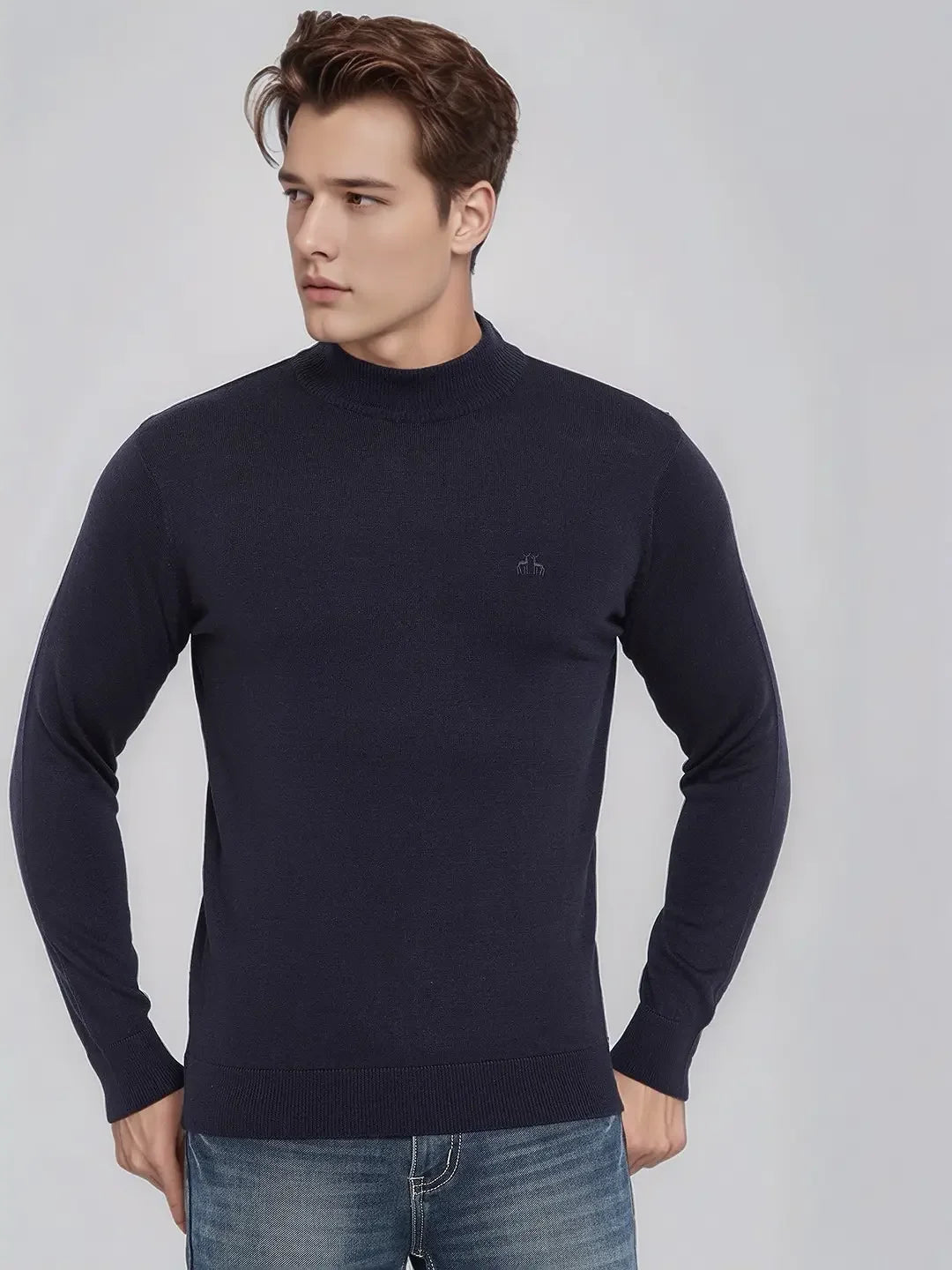 A man in a 98degreenorth Men’s Dark Navy Merino Wool Turtle Neck Sweater and blue jeans looks left against a plain background.