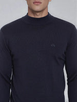 A man wears a 98degreenorth dark navy merino wool turtleneck sweater, fine-knit with a small chest logo.