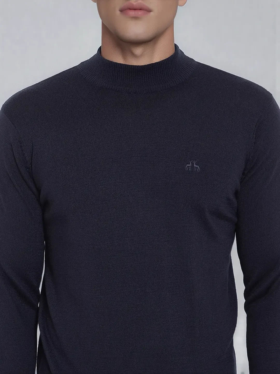 A man wears a 98degreenorth dark navy merino wool turtleneck sweater, fine-knit with a small chest logo.