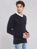 Young man in 98degreenorth Men’s Dark Navy Merino Wool V-Neck Sweater, white shirt, and light blue jeans, hands clasped.