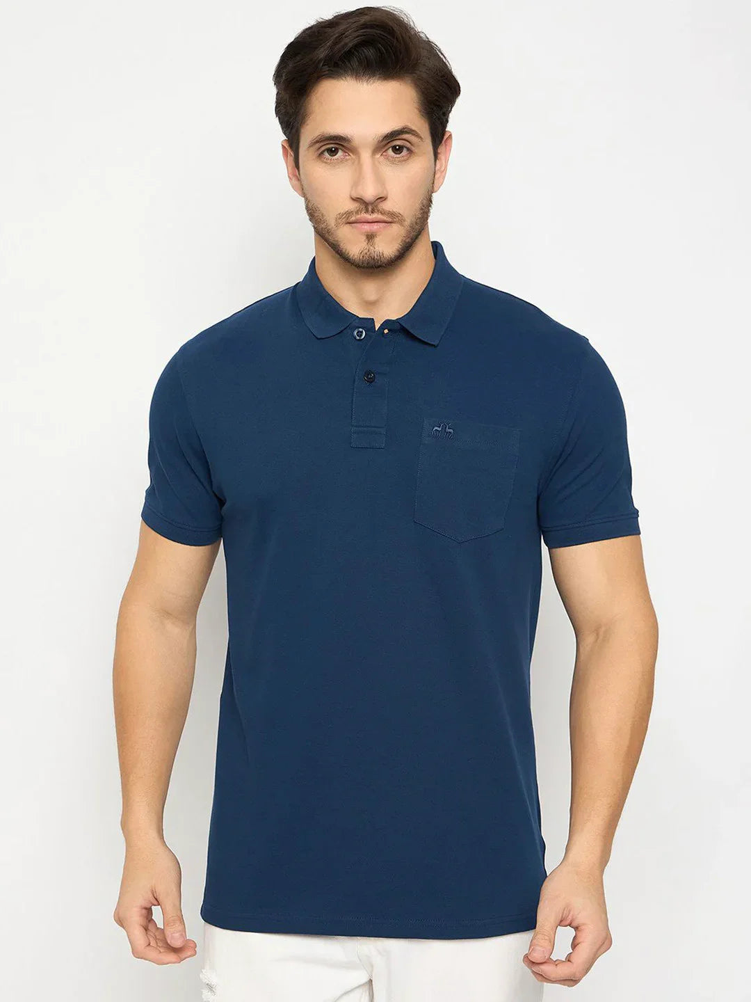 Man in 98degreenorth Men's Denim Blue Cotton Polo with chest pocket and white pants, on plain white background.