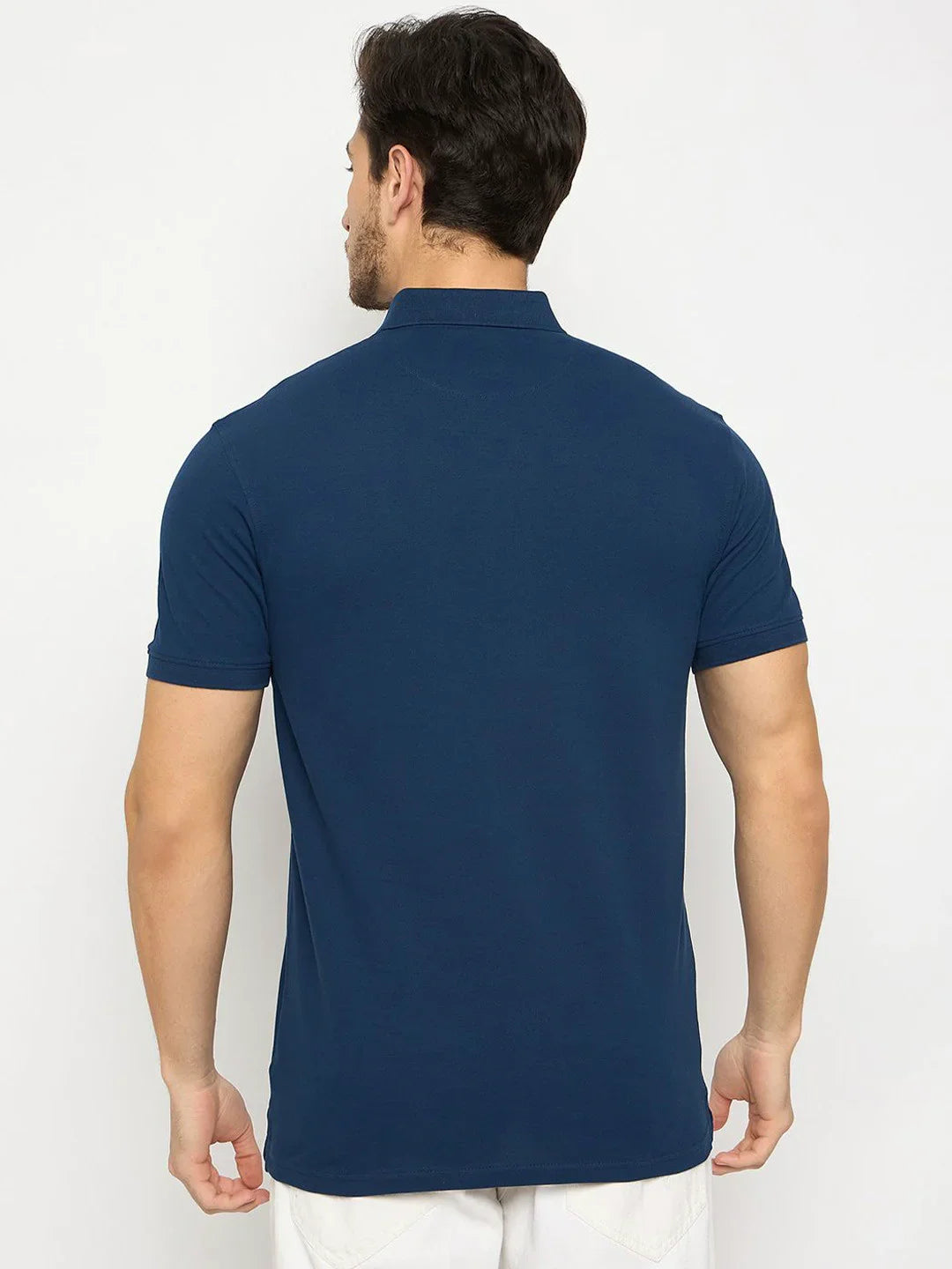 A man wears the 98degreenorth Men's Denim Blue Polo T-Shirt, pure cotton pique with chest pocket, shown from the back.