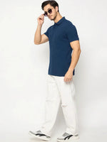 Man wearing 98degreenorth Men's Denim Blue Solid Polo T-Shirt stands against a plain white background.