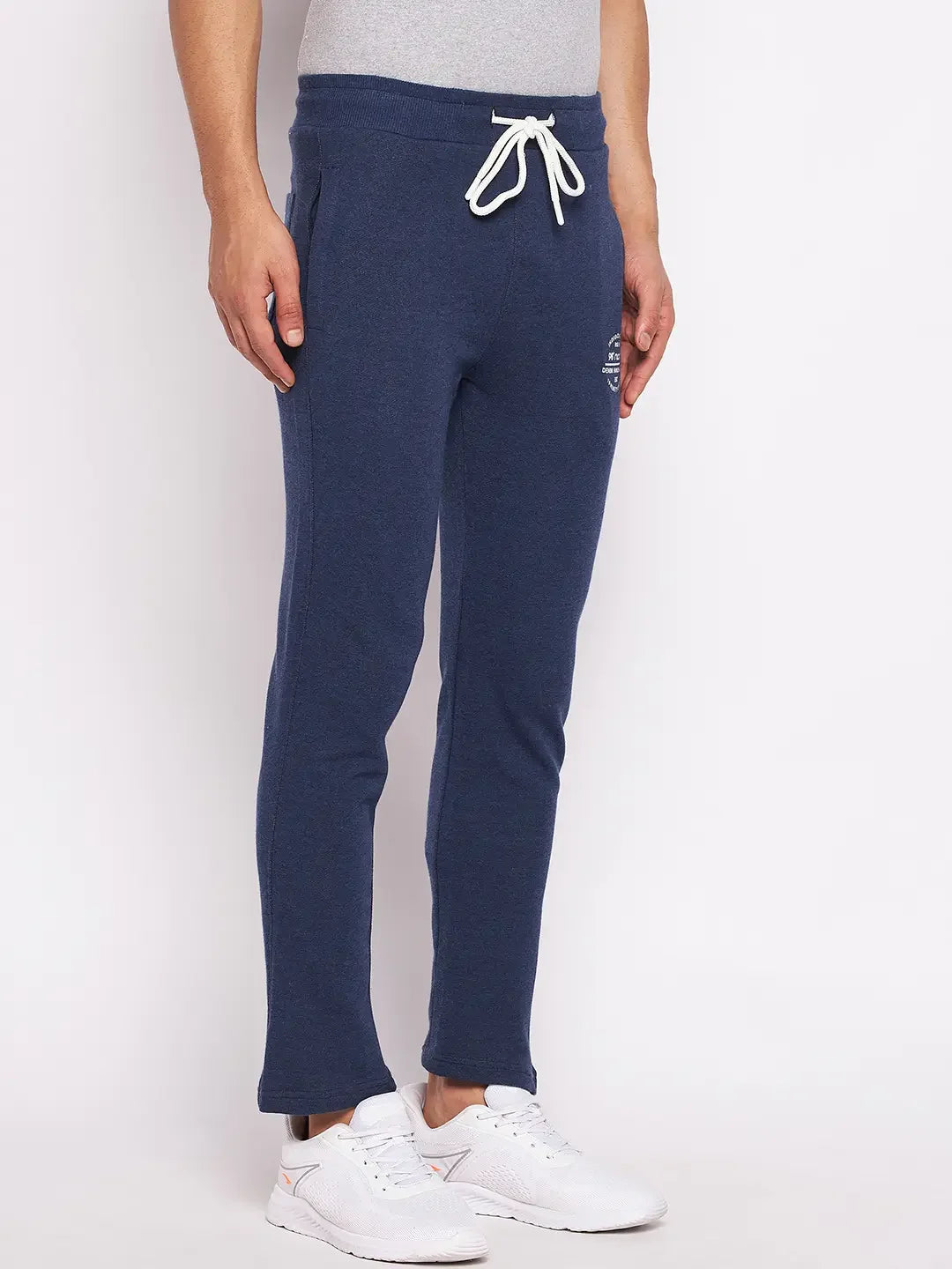 A person wears 98degreenorth Men’s Denim Fleece Trackpants, trendy knit joggers, with sneakers against a plain background.