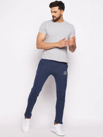 Man in 98degreenorth Men’s Denim Fleece Trackpants, grey tee, and white sneakers against a white background.