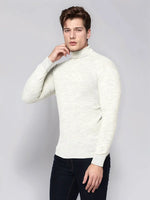 Man wears 98degreenorth Men’s Ecru Merino Wool Turtle Neck Sweater with dark jeans against a light grey background.
