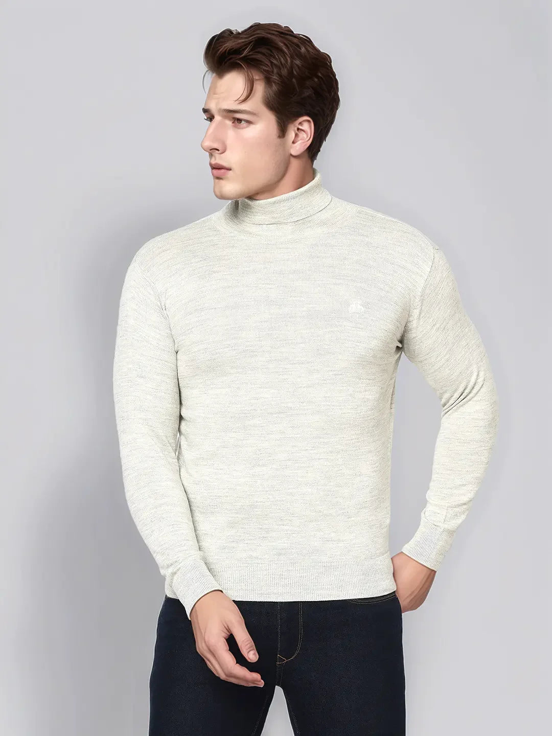 Man in 98degreenorth Ecru Merino Wool Turtle Neck Sweater, standing against a plain grey background, looking aside.