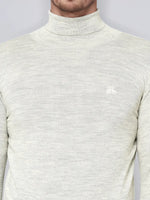 A man wears the 98degreenorth Men’s Ecru Merino Wool Turtle Neck Sweater with a small chest logo.