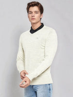 Young man in 98degreenorth Men’s Ecru Merino Wool V-Neck Sweater over a black shirt and blue jeans on a grey background.