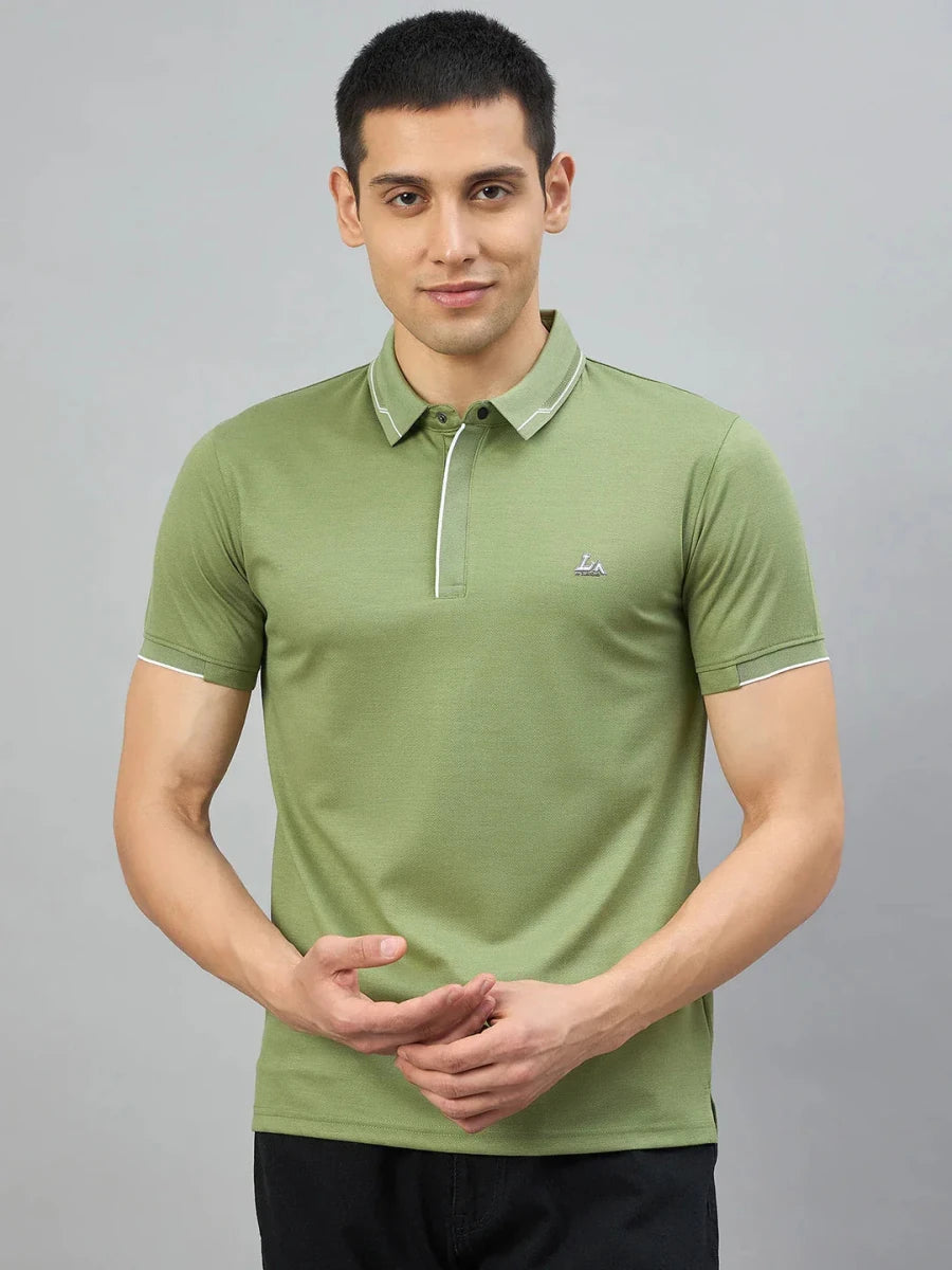 Man in 98degreenorth Men's Green Polo T-Shirt with White Tipping, standing against a plain gray background.