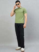 Man wears 98degreenorth Men's Green Polo T-Shirt with White Tipping, black pants, and white sneakers with sunglasses.