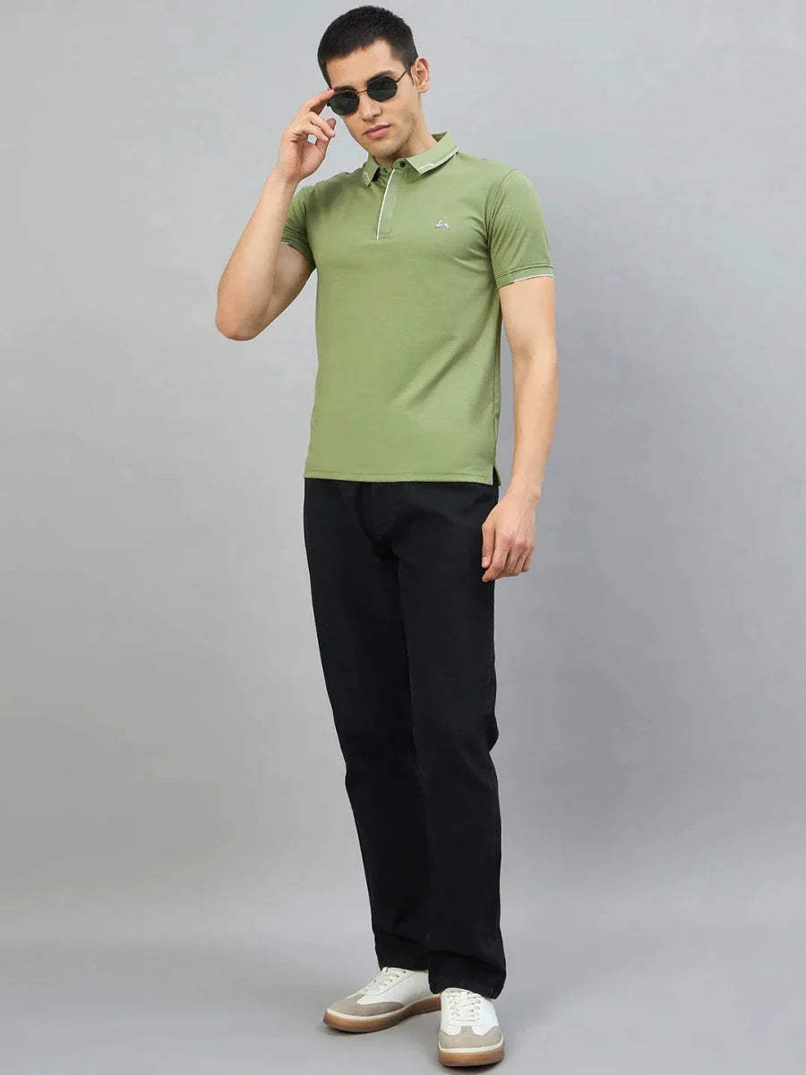 Man wears 98degreenorth Men's Green Polo T-Shirt with White Tipping, black pants, and white sneakers with sunglasses.