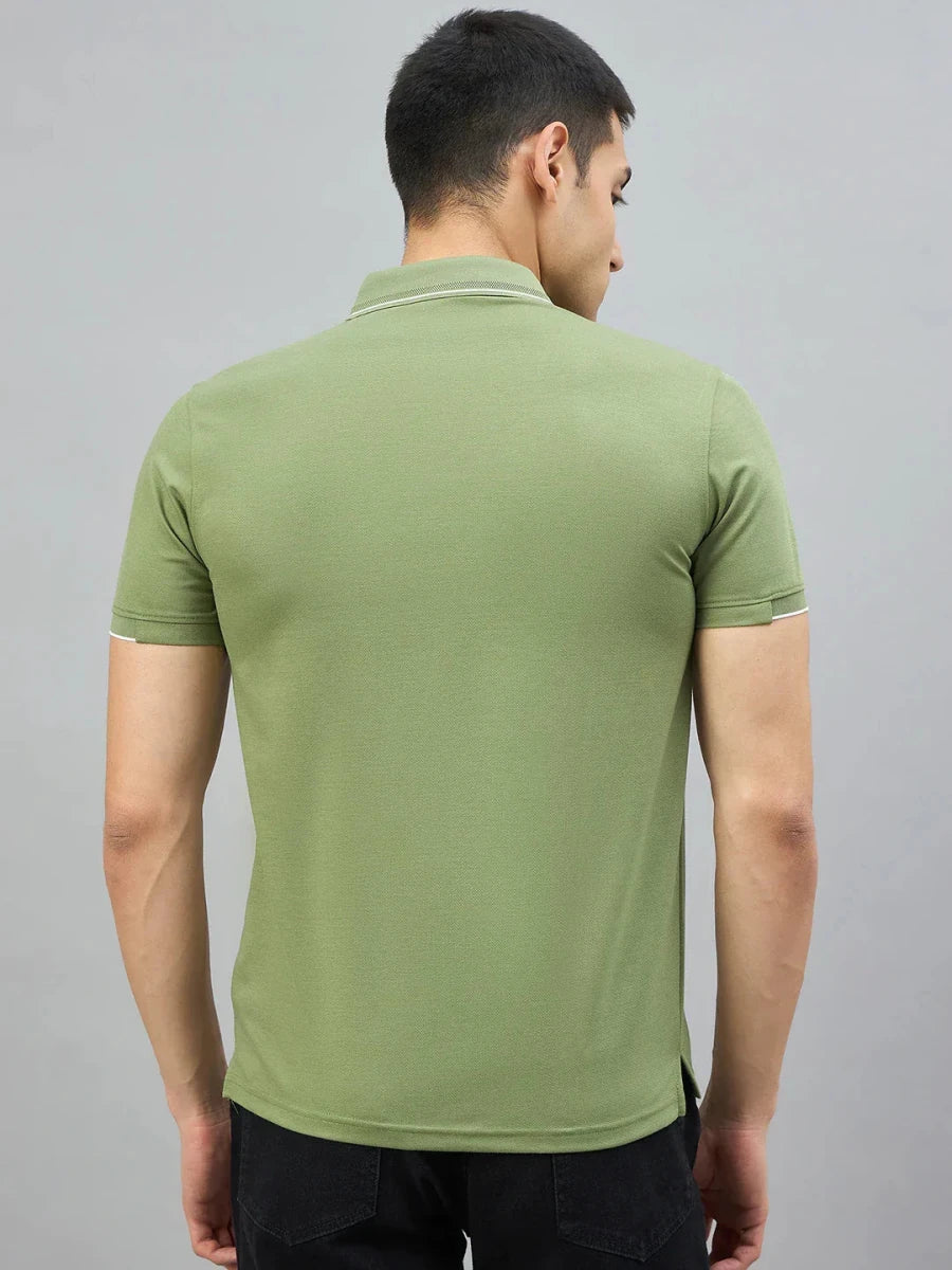 A man in a 98degreenorth Men's Green Polo T-Shirt with White Tipping stands stylishly against a gray backdrop.