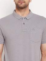 A man wears the 98degreenorth Men's Grey Polo T-Shirt in stretch cotton pique with chest pocket and small logo.