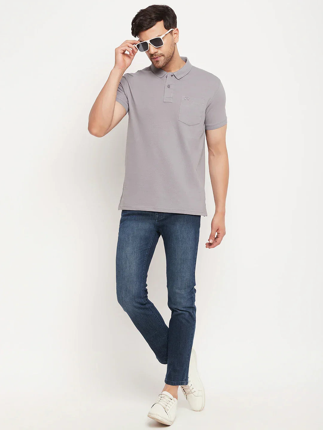 Man wearing 98degreenorth's grey stretch cotton pique polo T-shirt with chest pocket, blue jeans & white sneakers.