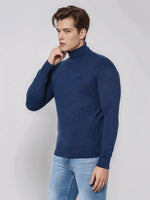 Young man wears 98degreenorth Light Denim Merino Wool Turtle Neck Sweater, standing against a plain light gray background.