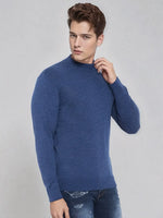A young man wears the 98degreenorth Men’s Light Denim Merino Wool Turtle Neck Sweater against a light gray background.