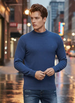 A man in a 98degreenorth Men’s Light Denim Merino Wool Turtle Neck Sweater stands on a wet city street at night.