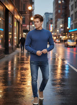A man wears a 98degreenorth Men’s Light Denim Merino Wool Turtle Neck Sweater on a wet city street at dusk.