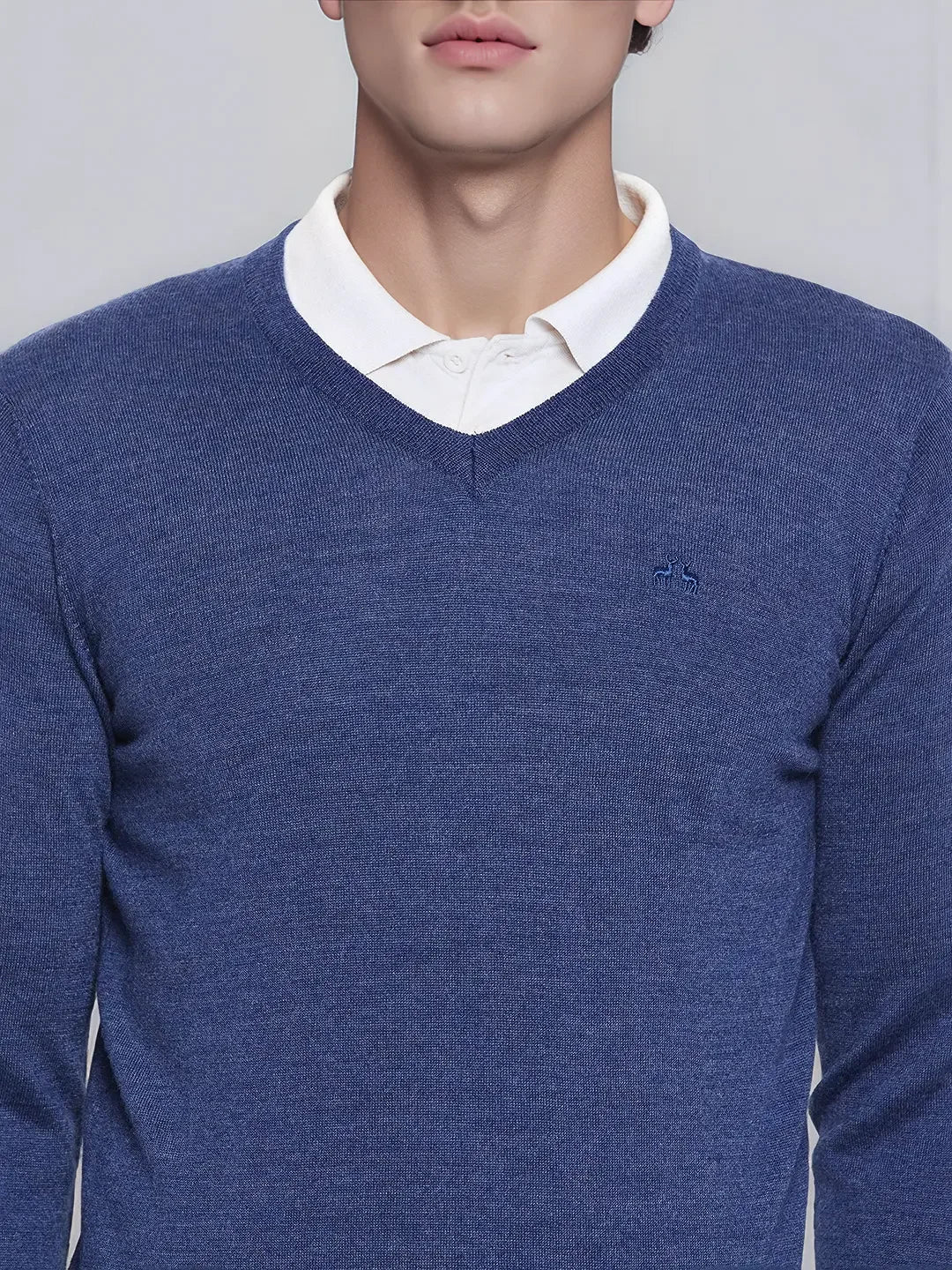 A man wears the 98degreenorth Men’s Light Denim Merino Wool V-Neck Sweater over a white shirt for a smart casual look.