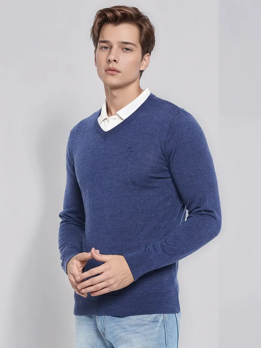 A man models the 98degreenorth Light Denim Merino V-Neck Sweater, styled smart casual over a white shirt.