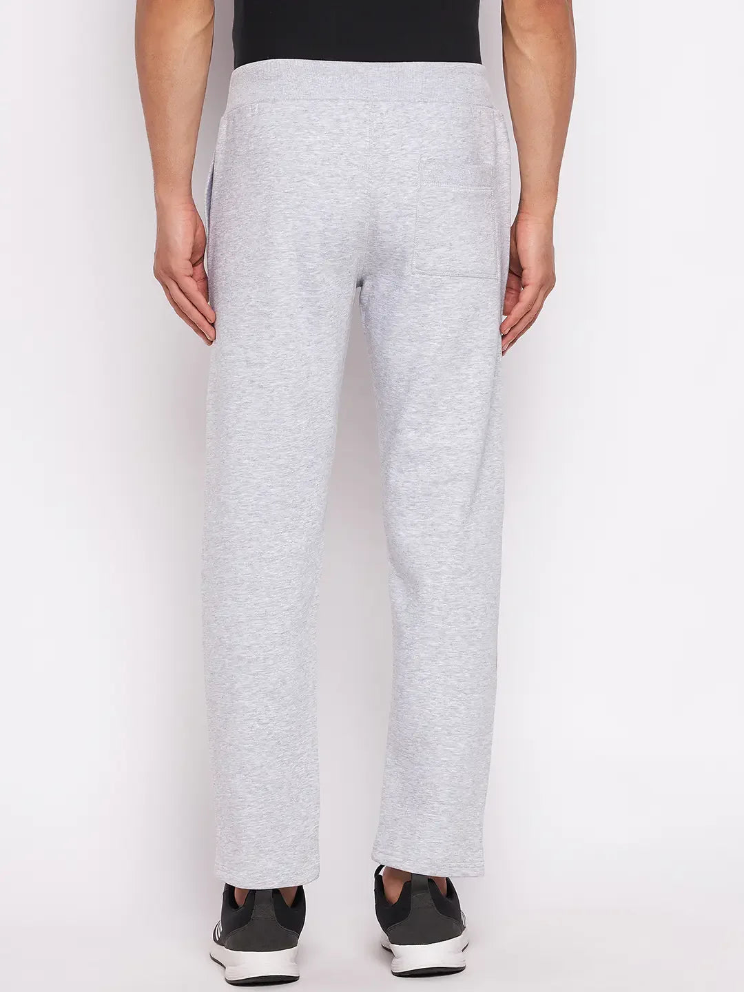 A person wears 98degreenorth Men’s Light Grey Fleece Trackpants with black sneakers, shown from the back.
