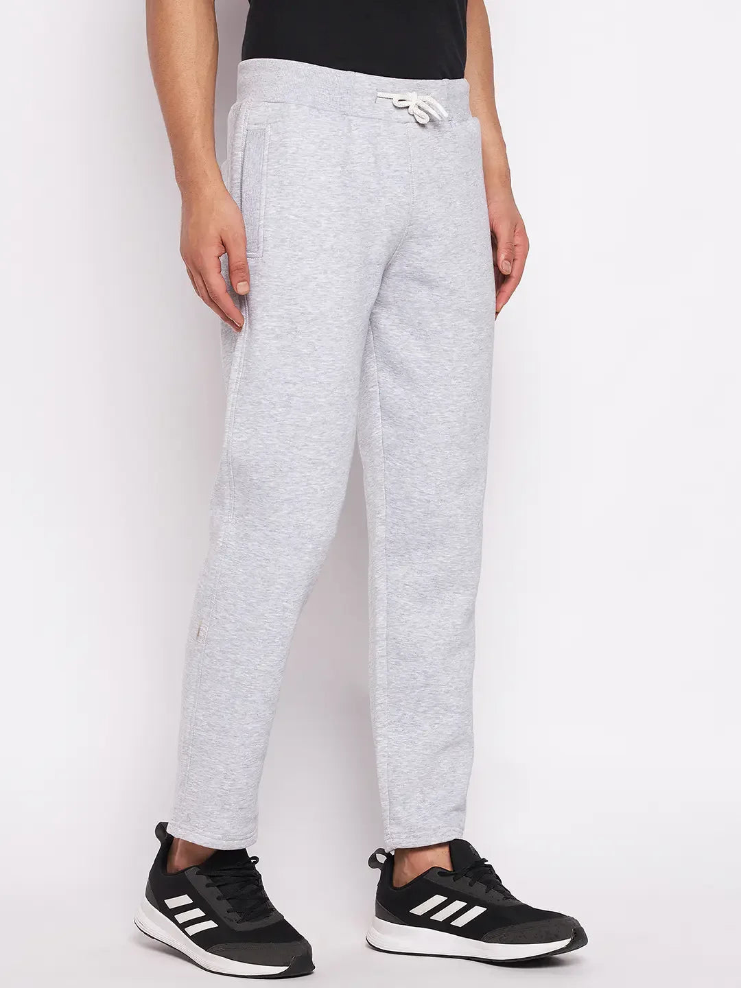 Man in 98degreenorth Men’s Light Grey Fleece Trackpants with drawstring, black tee, and Adidas sneakers, on white background.