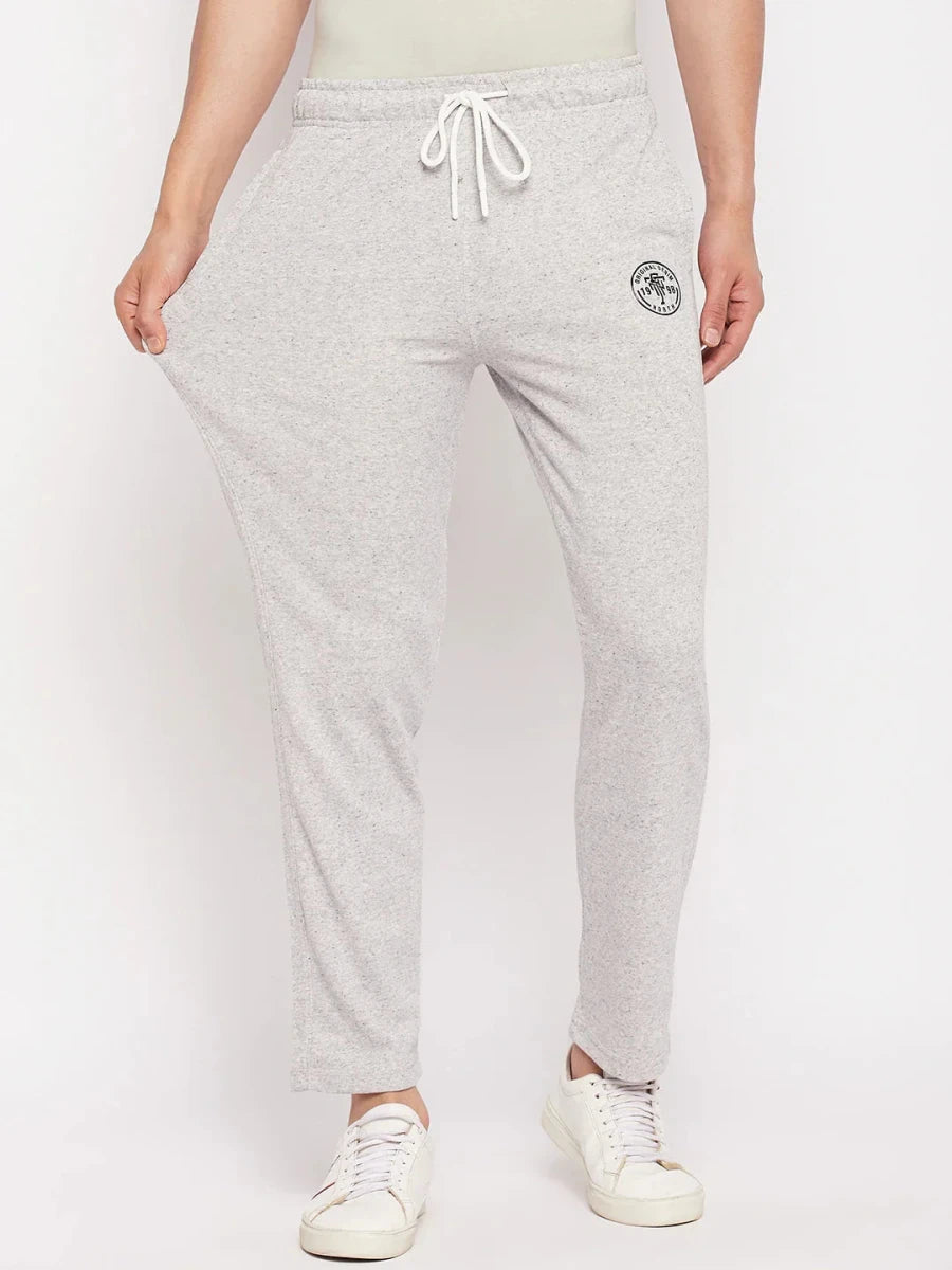 A man models 98degreenorth Men's Light Grey French Terry Lycra Trackpants, styled with white sneakers.