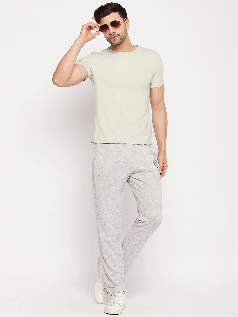 Man in sunglasses, beige tee, 98degreenorth Light Grey French Terry Lycra Trackpants, and white sneakers on white backdrop.