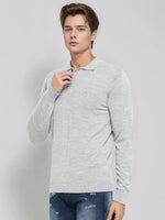 A young man in a 98degreenorth Men’s Light Grey Merino Wool Polo Sweater and blue jeans poses against a plain background.