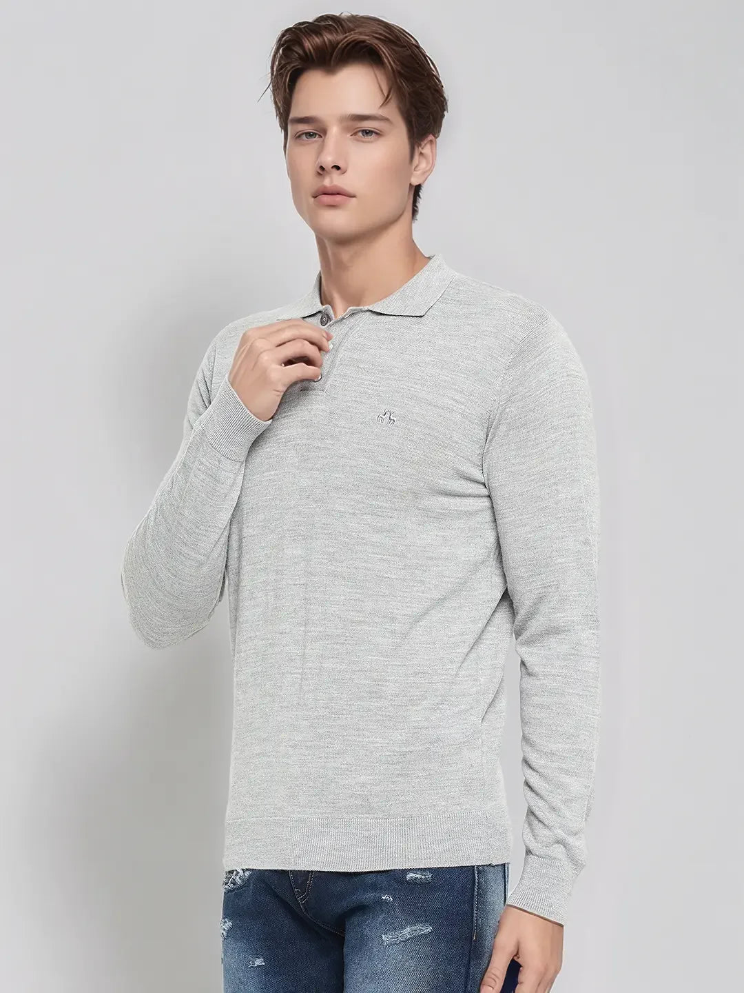 A young man in a 98degreenorth Men’s Light Grey Merino Wool Polo Sweater and blue jeans poses against a plain background.