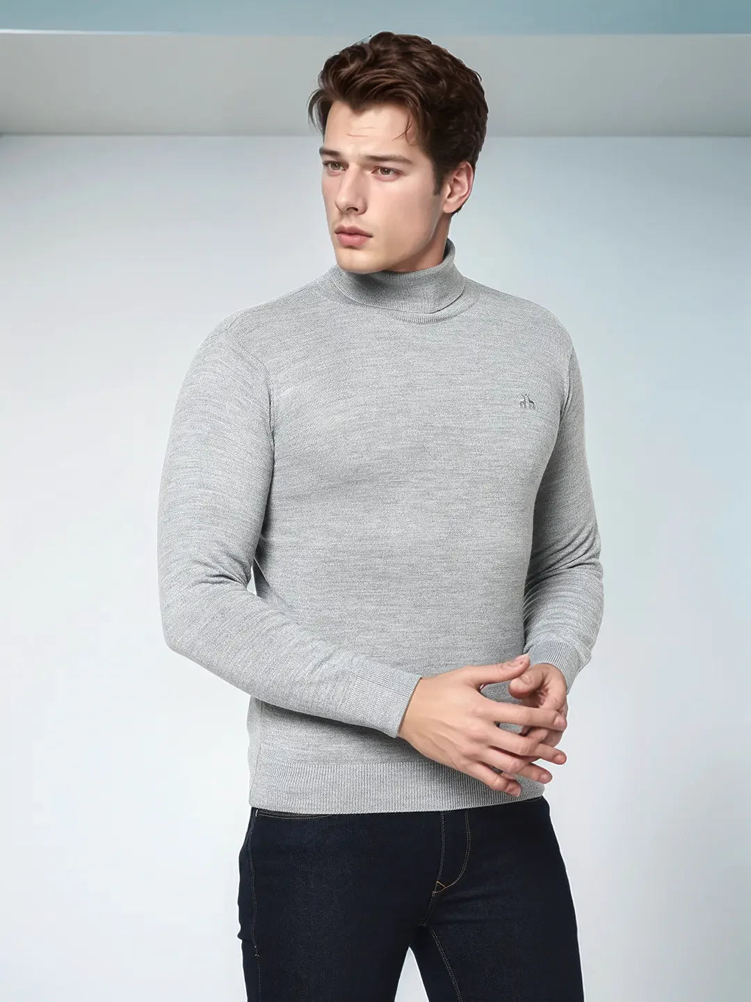 A man wears a 98degreenorth Men’s Light Grey Merino Wool Turtle Neck Sweater against a light background.