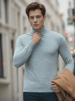 A man in a 98degreenorth Light Grey Merino Wool Turtle Neck holds a tan coat while standing on a city street.