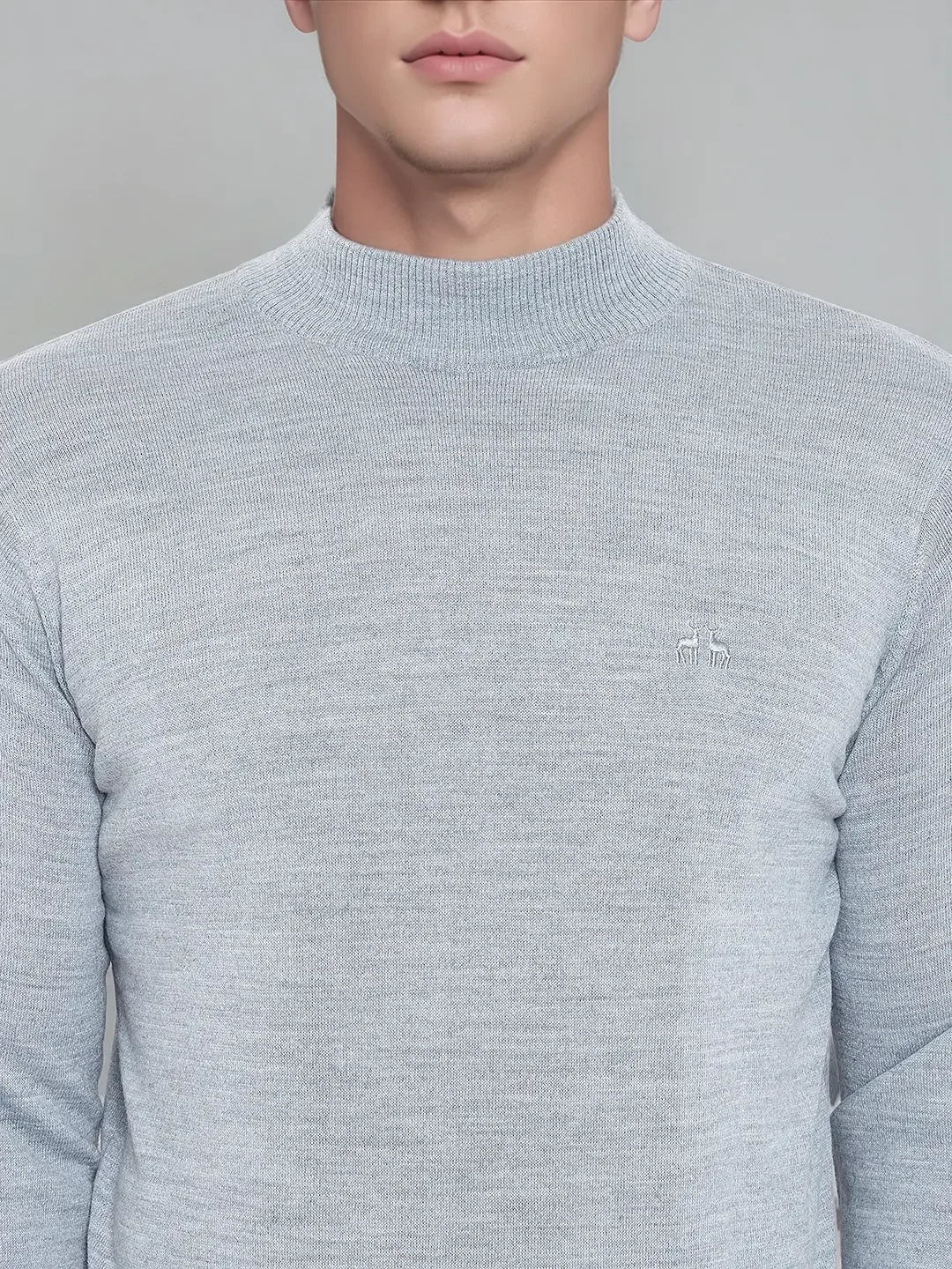 A man wears a 98degreenorth light grey merino wool turtleneck sweater, shown shoulder to mid-torso.