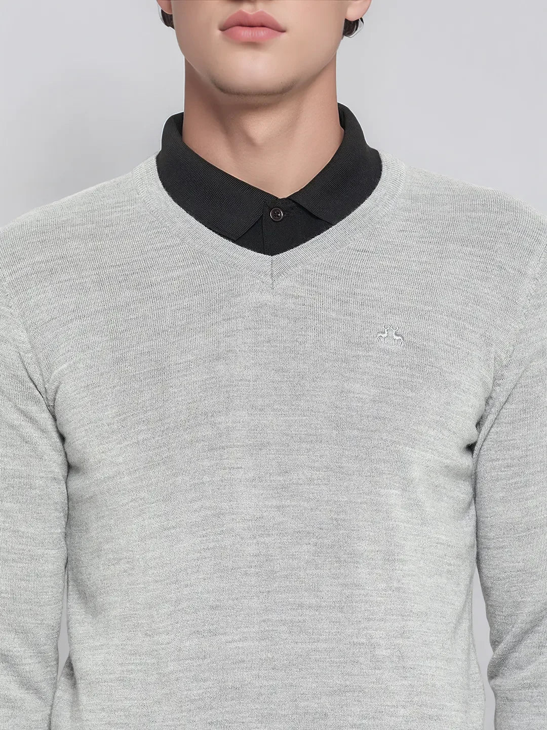 A man wears the 98degreenorth Men’s Light Grey Merino Wool V-Neck Sweater over a black shirt, shown shoulders to mouth.