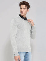 Man wearing 98degreenorth Men’s Light Grey Merino Wool V-Neck Sweater over a black shirt and light blue jeans.