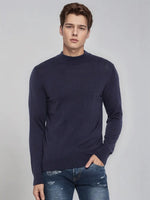 Young man in a 98degreenorth Men’s Light Navy Merino Wool Turtle Neck Sweater, standing with a hand in his pocket.