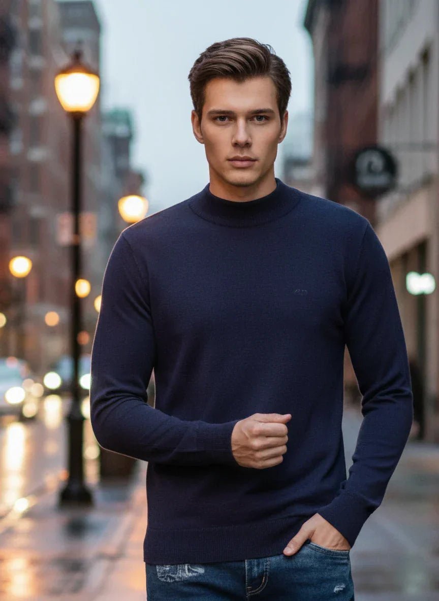 A man wears the 98degreenorth Men’s Light Navy Merino Wool Turtle Neck Sweater on a city street at dusk.