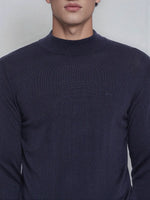A man wears a 98degreenorth Light Navy Merino Wool Turtle Neck Sweater, shown from shoulders to upper chest.