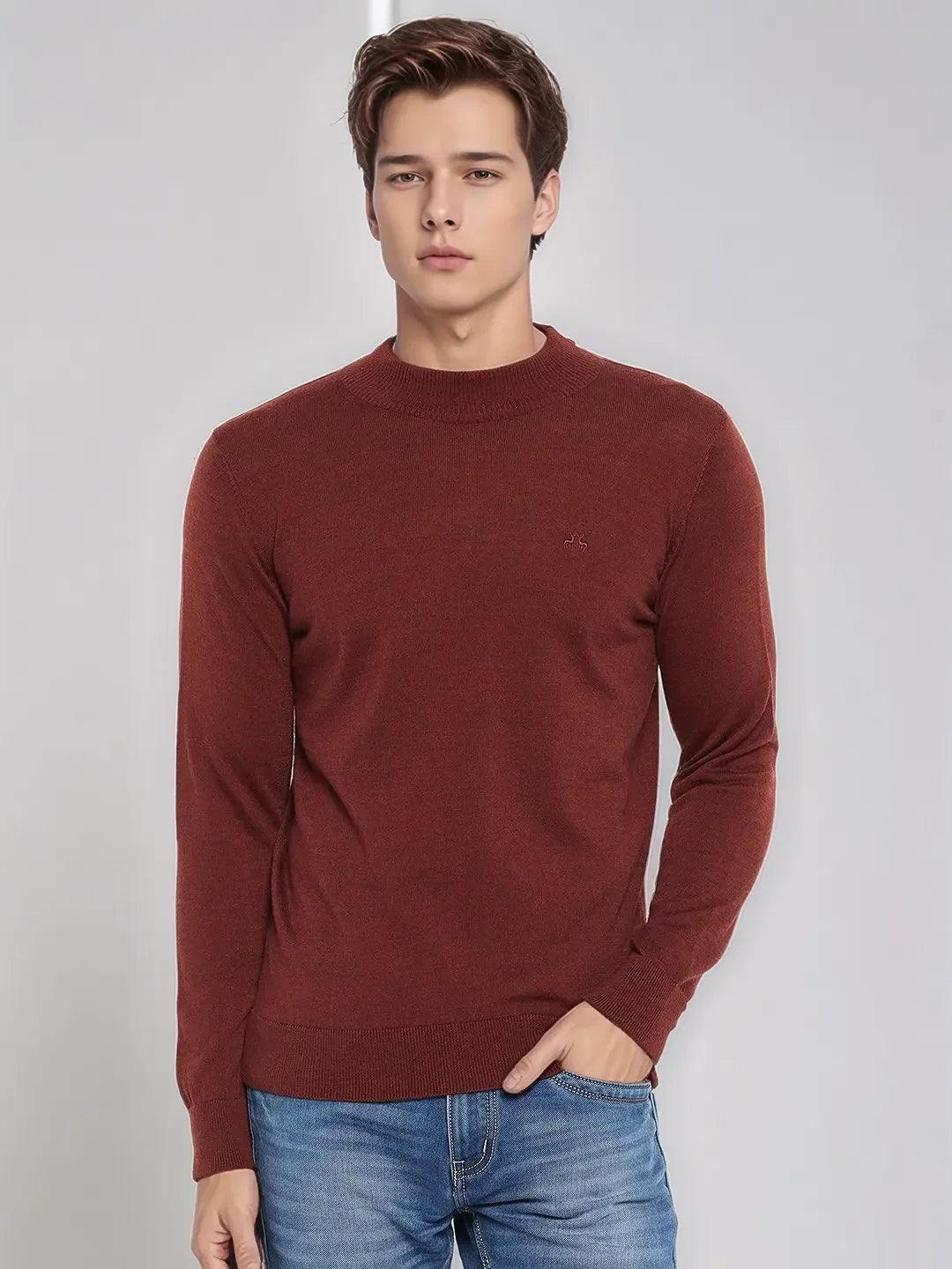 A man in a 98degreenorth maroon Merino wool turtleneck sweater and blue jeans stands against a light gray background.