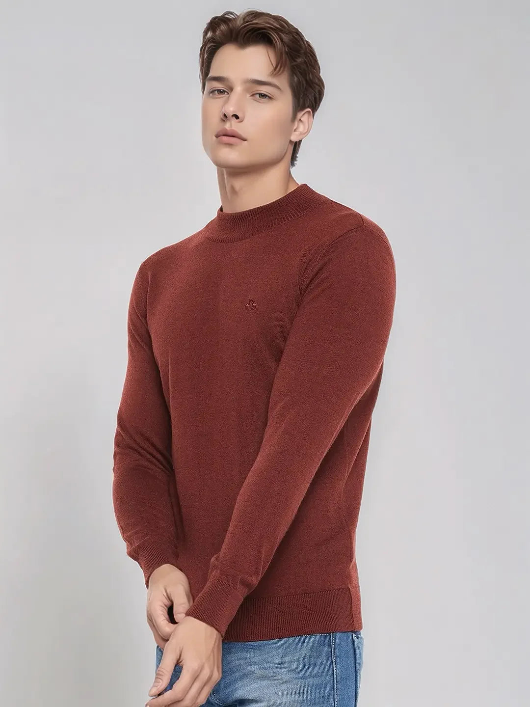A young man wears a 98degreenorth maroon Merino wool turtle neck sweater with blue jeans against a light gray background.