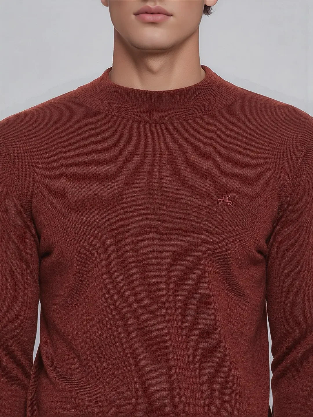 A man wears the 98degreenorth Men’s Maroon Merino Wool Turtle Neck Sweater, shown mid-torso with a small logo.